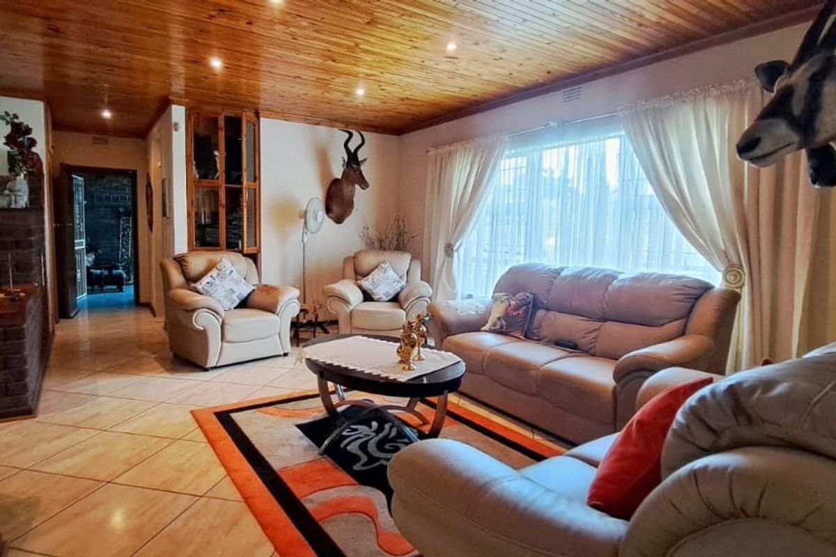 Spacious living room featuring warm timber tongue and groove ceilings, ceramic floor tiling, and recessed downlighting, creating a comfortable and inviting atmosphere.