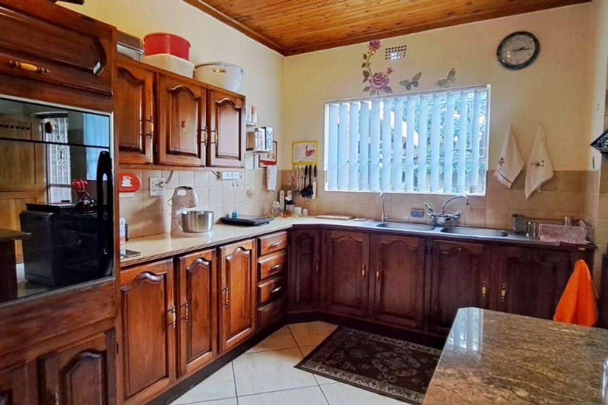 A traditional kitchen featuring solid wood cabinetry, granite countertops, a double basin sink, and a timber ceiling, offering a classic aesthetic.