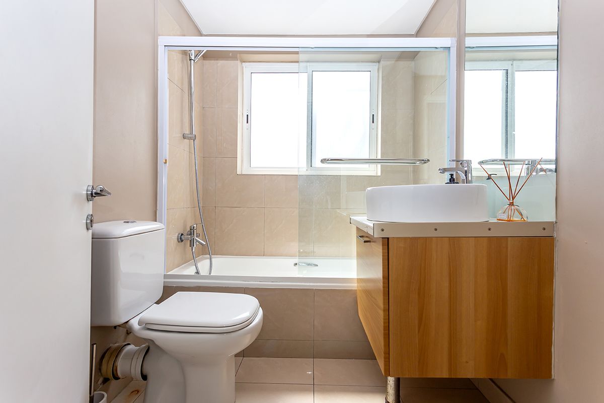 A functional bathroom featuring a combined shower and bathtub, a modern vessel sink vanity, and neutral wall tiling.