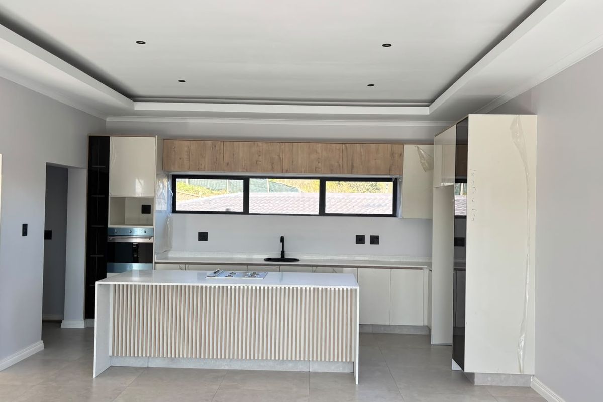 Modern kitchen featuring a central island with hob, sleek built-in cabinetry, integrated oven, and contemporary finishes in a bright, open-plan space.