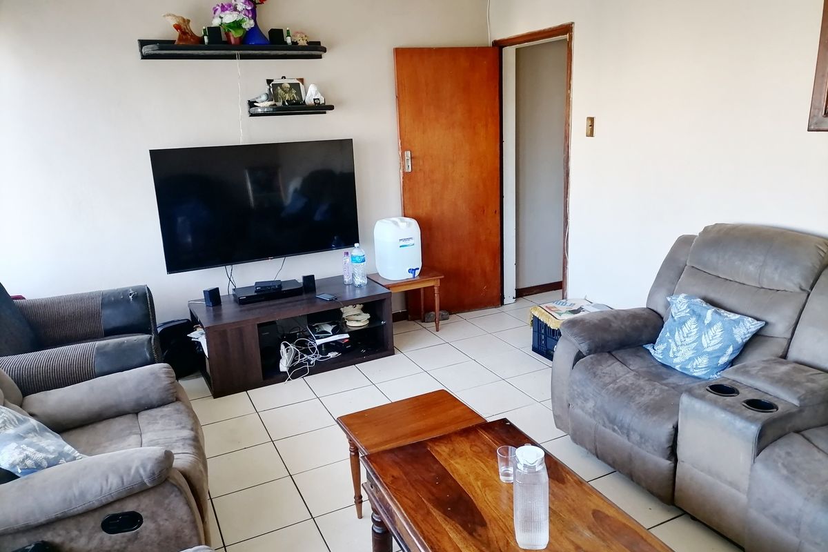 A living room featuring ceramic floor tiles and a standard wooden interior door, providing a functional and accessible living space.