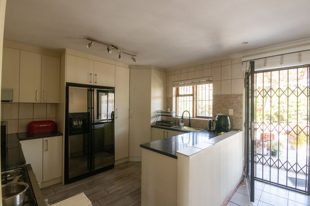Functional kitchen featuring granite countertops, built-in cabinetry, double sink, and direct access to the exterior through a security gate.