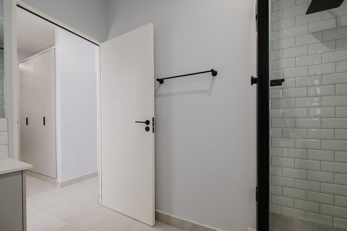 Modern bathroom featuring a glass-enclosed shower with white subway tiles, matte black fixtures, and a clean, minimalist aesthetic.
