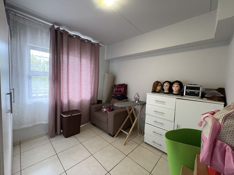 A bedroom featuring tiled flooring and a built-in wardrobe, offering a functional space with natural light from the window.