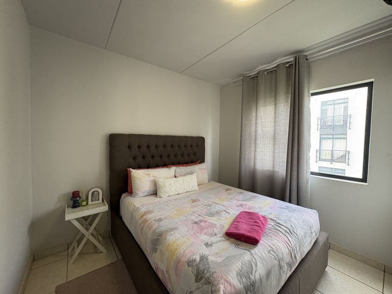 A functional bedroom featuring tiled flooring and a window with curtain tracks, providing a neutral space ready for personalization.