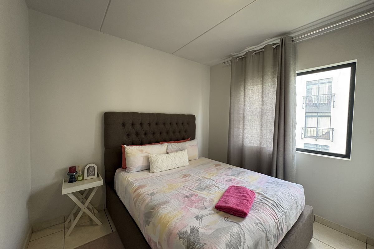 A functional bedroom featuring tiled flooring and a window with curtain tracks, providing a neutral space ready for personalization.