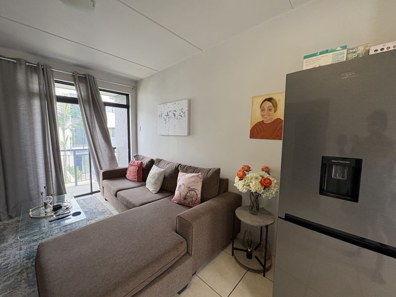 Open plan living area featuring tiled flooring and a sliding glass door providing access to a balcony.
