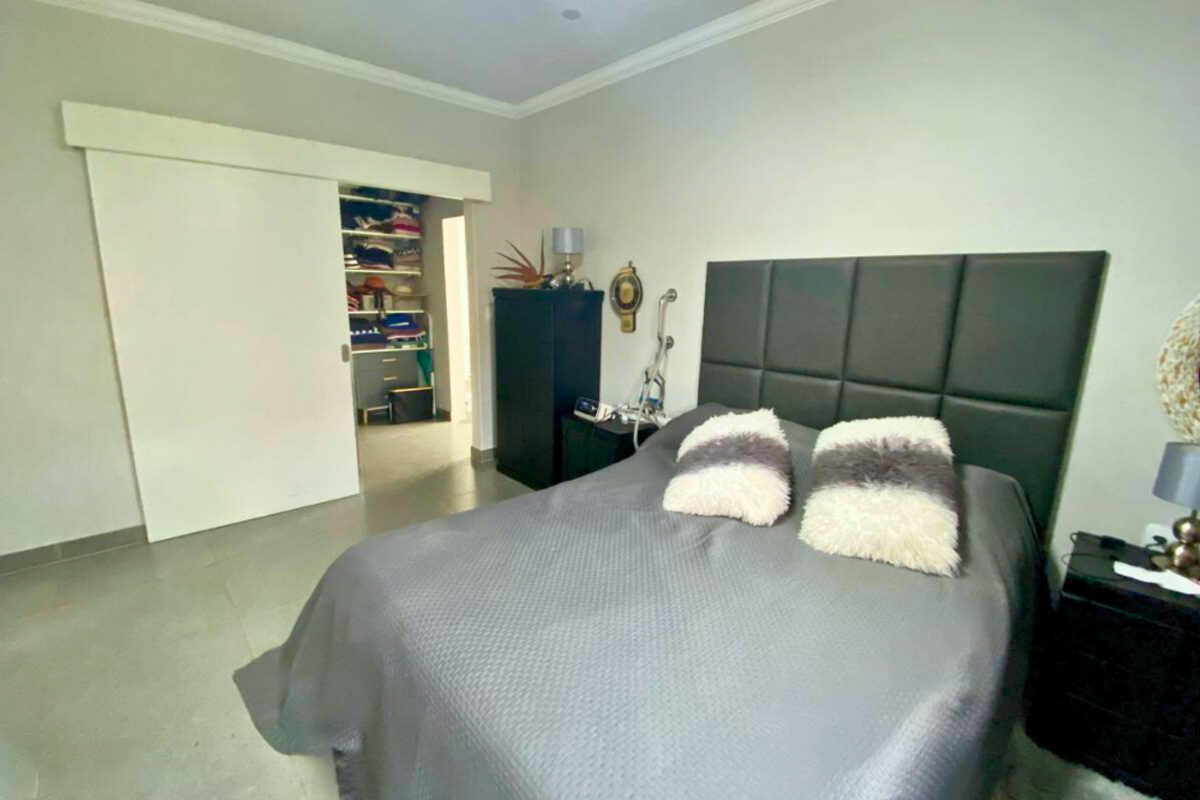 A bedroom featuring tiled flooring, crown molding, and a sliding door leading to a walk-in closet area.