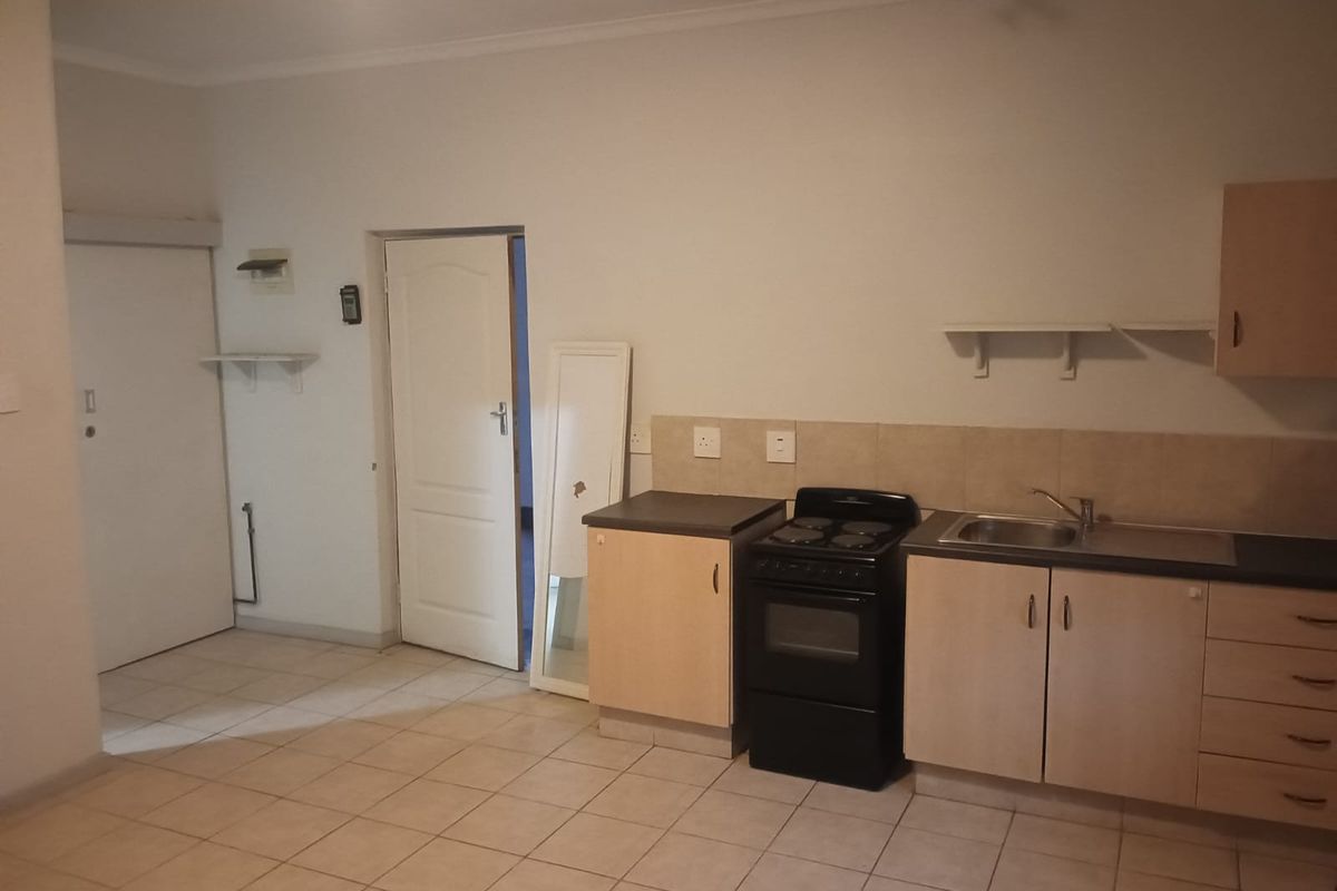 A functional kitchen area featuring light wood cabinetry, a built-in stove, stainless steel sink, and tiled flooring.