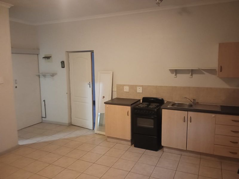 A functional kitchen area featuring light wood cabinetry, a built-in stove, stainless steel sink, and tiled flooring.