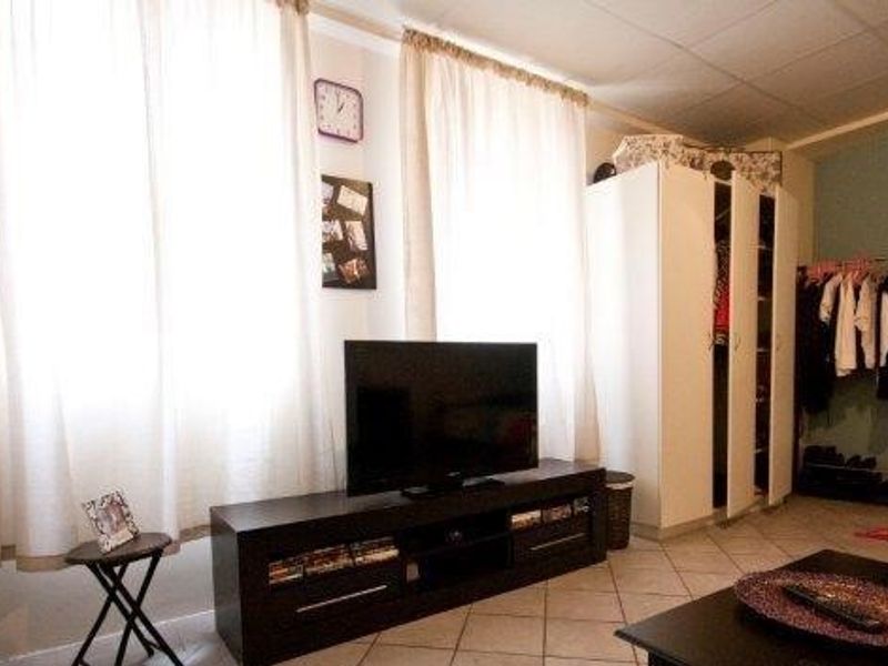A bedroom featuring tiled flooring, built-in wardrobe storage, and large windows allowing for natural light.