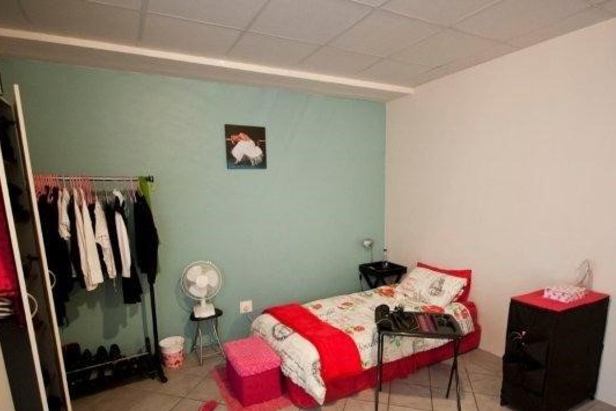 A bedroom featuring tiled flooring and a painted accent wall, providing a functional space for rest.