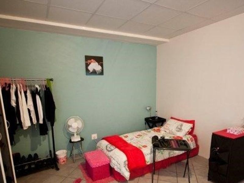 A bedroom featuring tiled flooring and a painted accent wall, providing a functional space for rest.