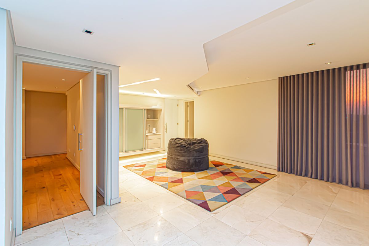 Spacious living area featuring polished marble flooring, recessed ceiling lighting, and integrated cabinetry, leading into a secondary room with timber flooring.
