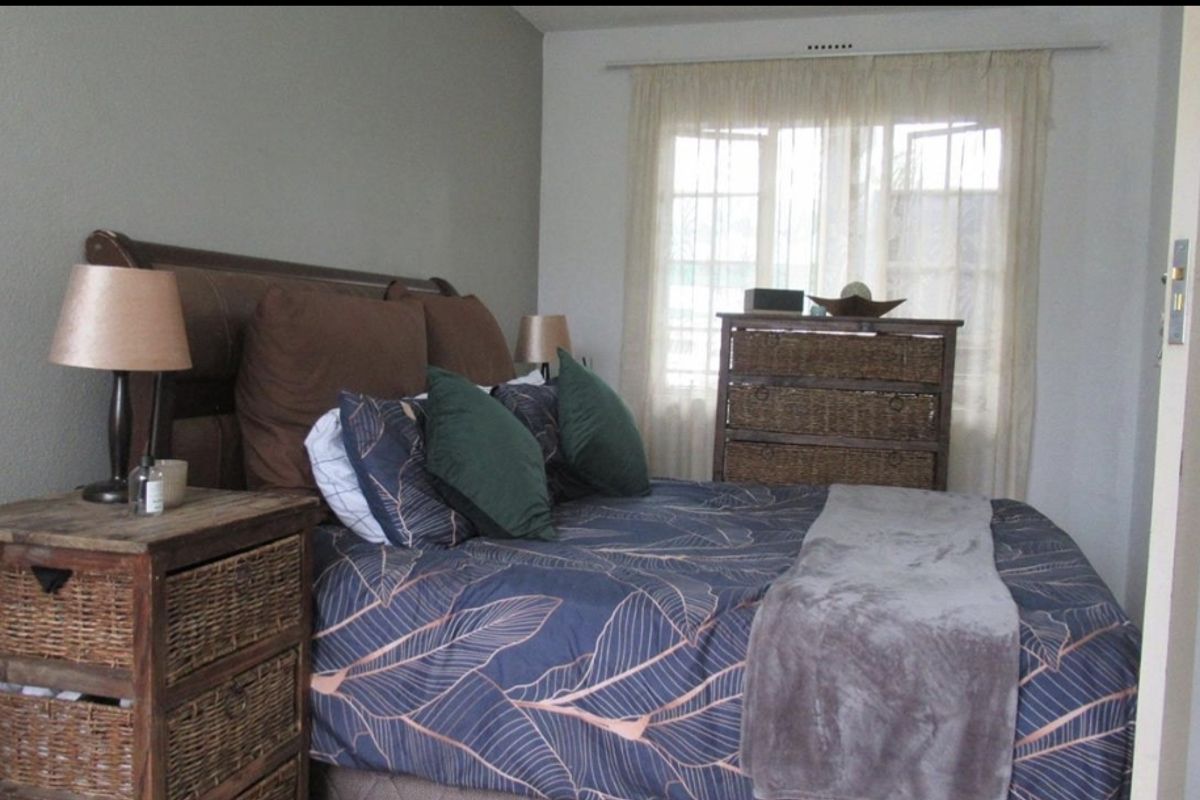 A cozy bedroom featuring a window with curtain tracks and neutral wall finishes.