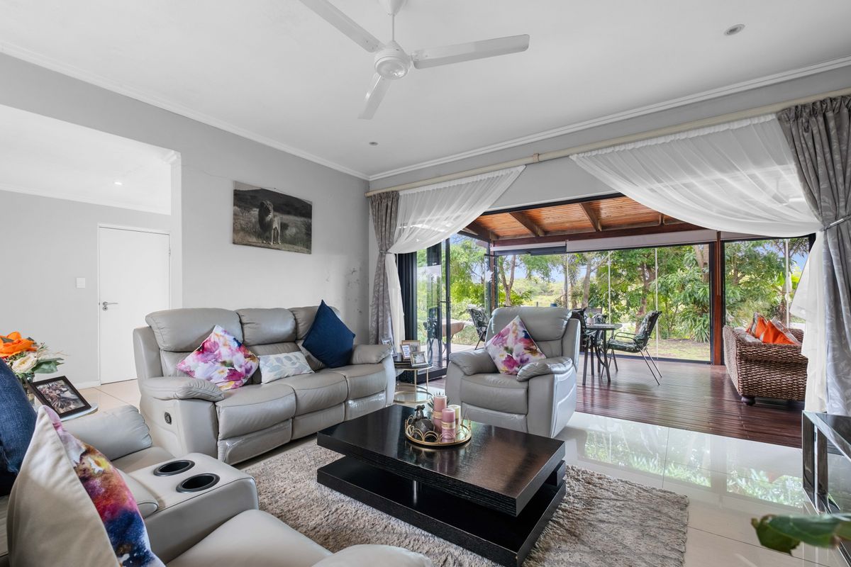 Spacious living room featuring large sliding glass doors that open onto a covered wooden deck, creating a seamless indoor-outdoor flow.