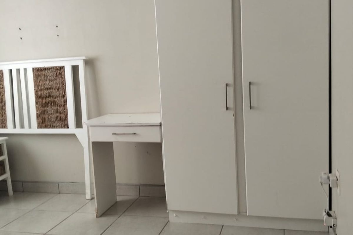 A bedroom featuring built-in white cabinetry and tiled flooring, offering a functional space with neutral finishes.