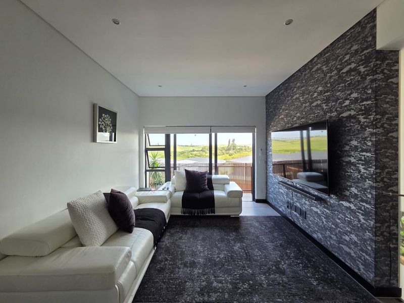 Modern living room featuring a textured feature wall, recessed lighting, and large sliding glass doors providing natural light and access to the balcony.