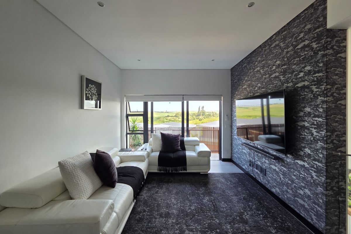 Modern living room featuring a textured feature wall, recessed lighting, and large sliding glass doors providing natural light and access to the balcony.