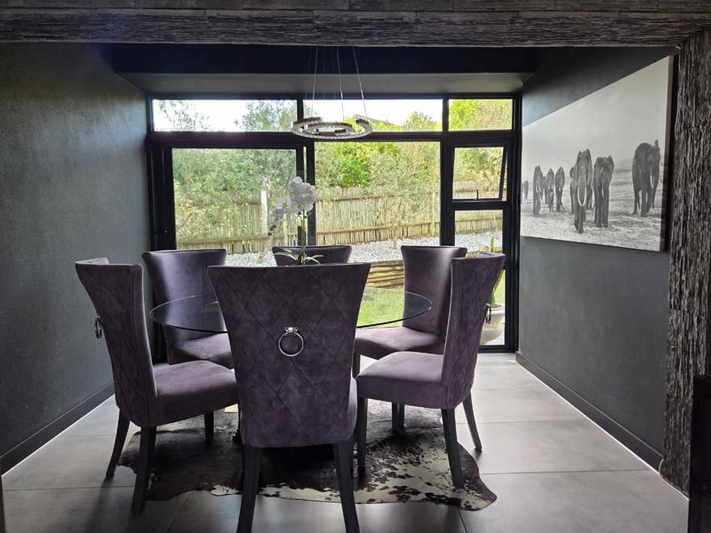 A modern dining room featuring large glass sliding doors that provide natural light and views of the garden, complemented by sleek tiled flooring.