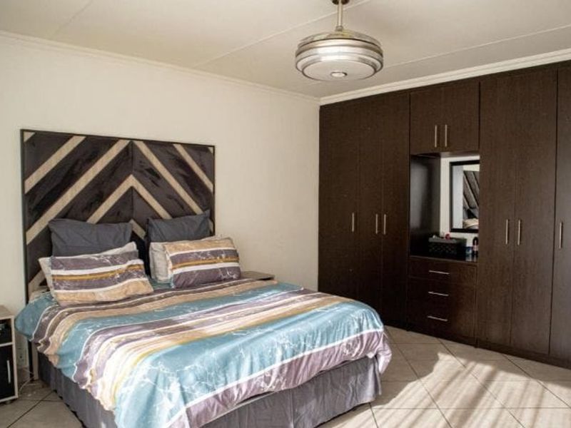 A well-maintained bedroom featuring extensive dark wood built-in cabinetry with integrated vanity and tiled flooring.