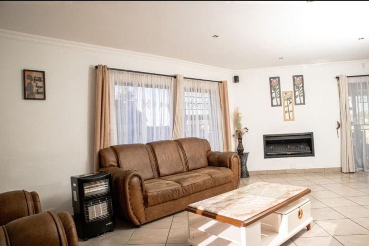 Spacious living room featuring tiled flooring, a built-in fireplace, and large windows with natural light, creating a comfortable and inviting atmosphere.
