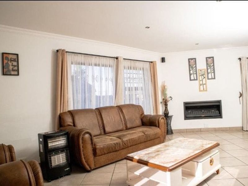 Spacious living room featuring tiled flooring, a built-in fireplace, and large windows with natural light, creating a comfortable and inviting atmosphere.