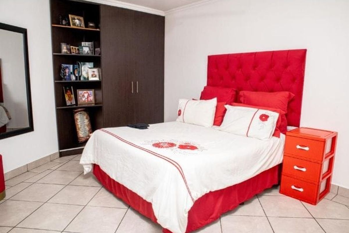 A bedroom featuring built-in dark wood cabinetry with integrated shelving and tiled flooring.
