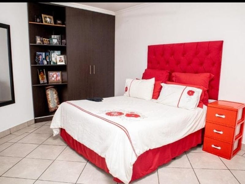 A bedroom featuring built-in dark wood cabinetry with integrated shelving and tiled flooring.