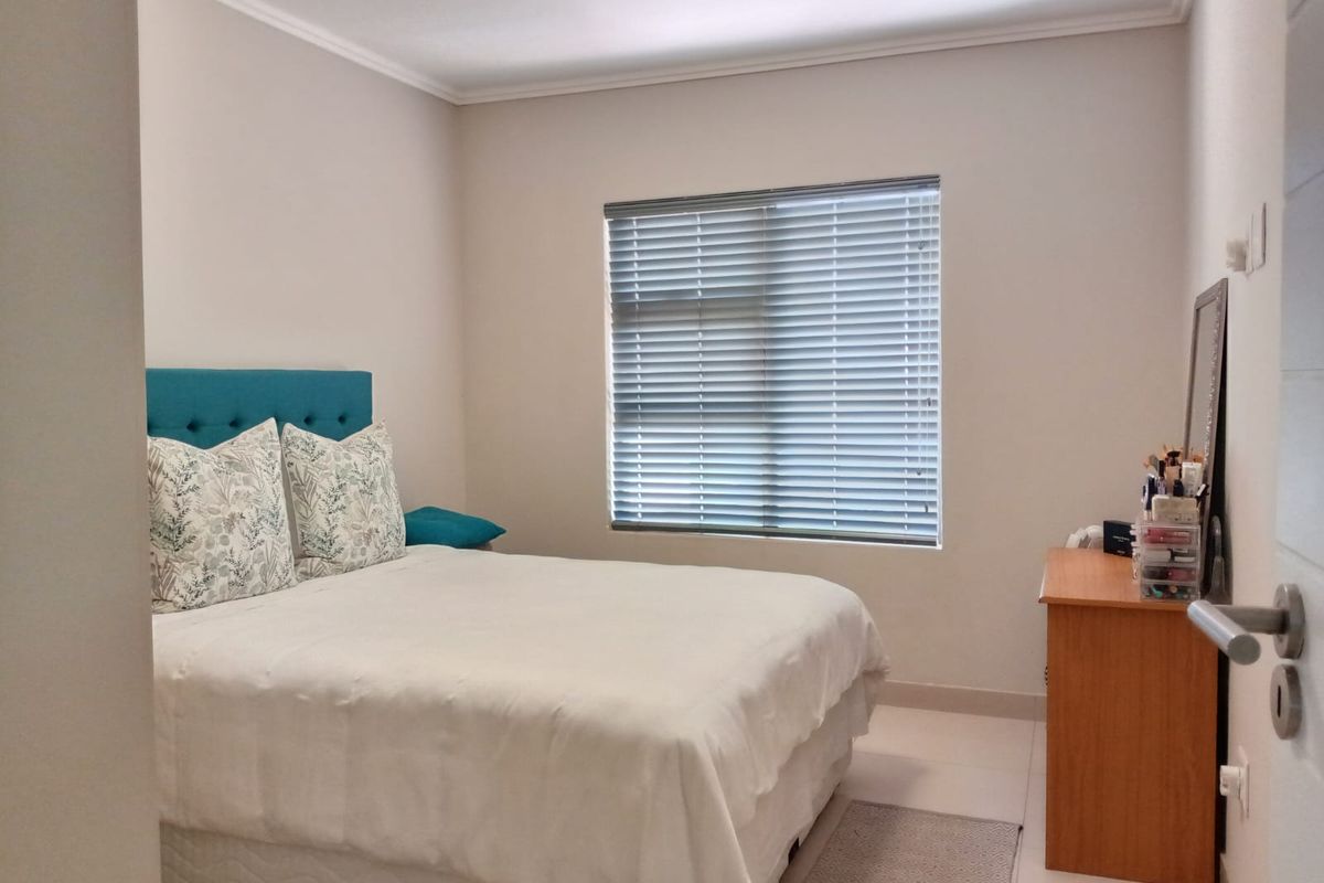 A well-maintained bedroom featuring neutral wall finishes, tiled flooring, and fitted venetian blinds.