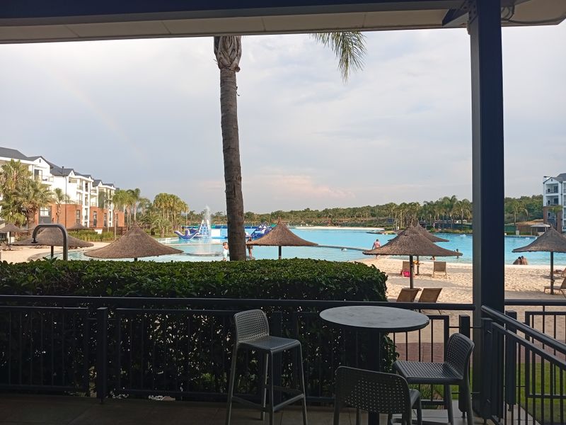 A covered patio area overlooking a large communal swimming pool and landscaped estate grounds.