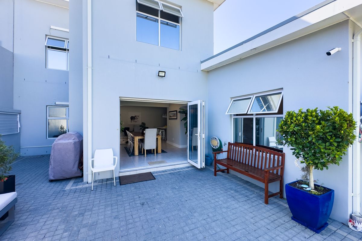 A well-maintained rear courtyard featuring paved flooring, bi-fold doors providing access to the interior, and secure exterior lighting.