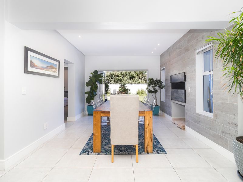 Spacious dining area featuring a stone-clad feature wall, built-in fireplace, tiled flooring, and large sliding doors opening to the rear garden.