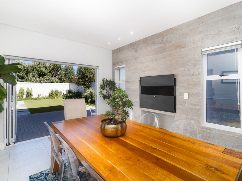 Modern living area featuring a stone-clad feature wall with a built-in fireplace and seamless access to the rear garden through stacking glass doors.