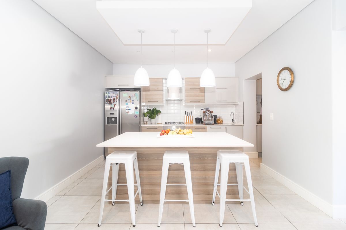 Modern kitchen featuring a central island with breakfast bar seating, sleek cabinetry, integrated appliances, and stylish pendant lighting.