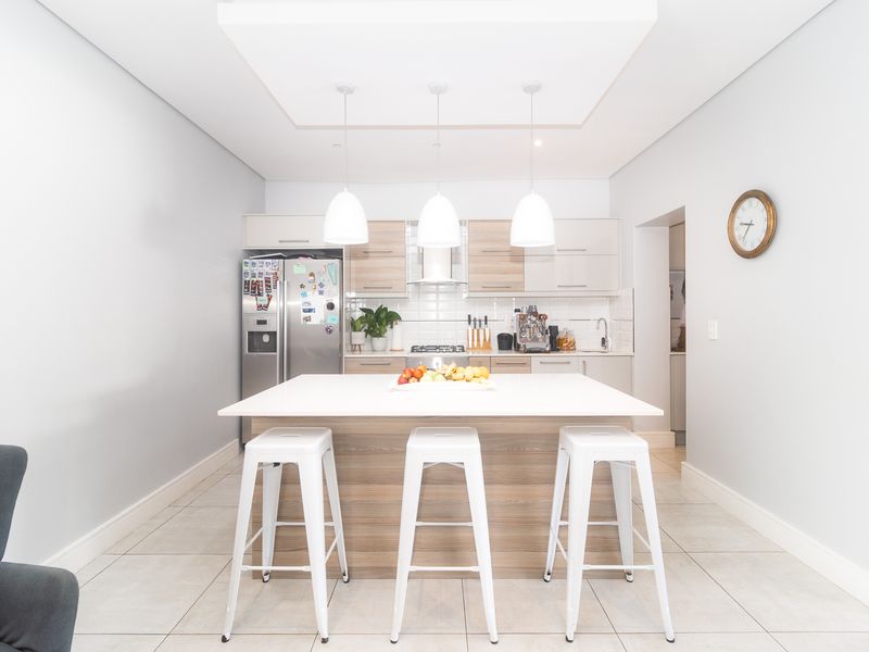 Modern kitchen featuring a central island with breakfast bar seating, sleek cabinetry, integrated appliances, and stylish pendant lighting.