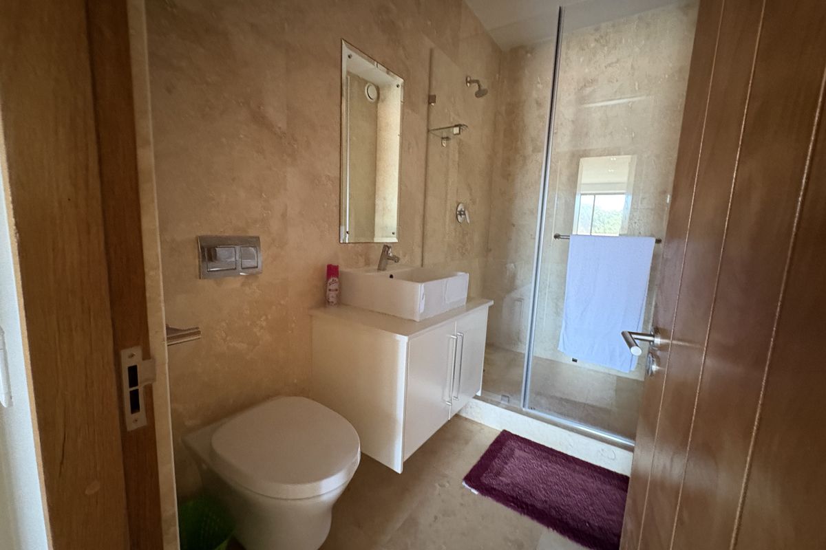 Modern bathroom featuring floor-to-ceiling stone tiling, a wall-mounted vanity with a vessel sink, a concealed cistern toilet, and a glass-enclosed walk-in shower.