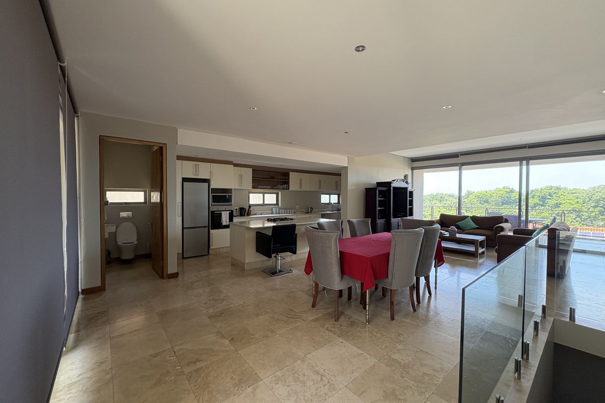 Spacious open-plan living area featuring a modern kitchen with built-in cabinetry, stone countertops, and seamless flow to the dining and lounge space.