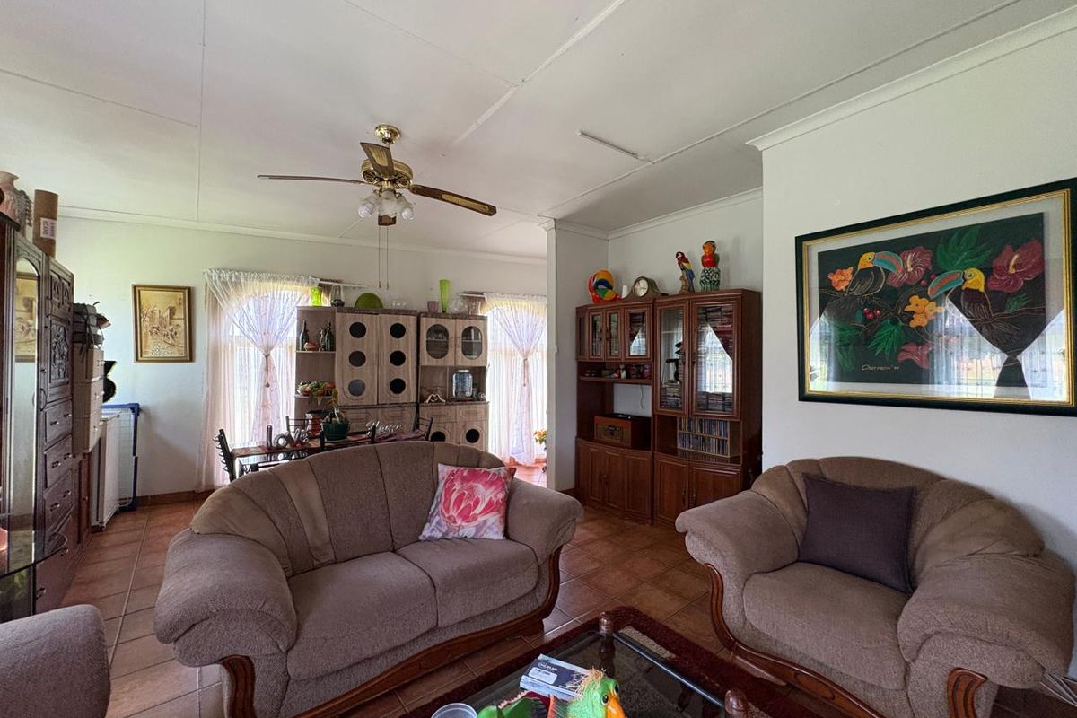 A spacious living area featuring tiled flooring and a ceiling fan, offering a comfortable layout with an open-plan flow to the adjacent dining space.