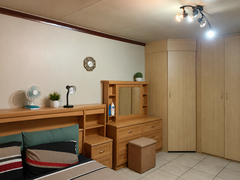 A bedroom featuring built-in wooden cupboards, tiled flooring, and a modern ceiling spotlight fixture.