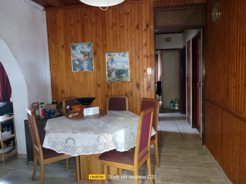 Dining area featuring traditional timber wall paneling and ceiling with tiled flooring, providing a dated aesthetic ready for modernization.