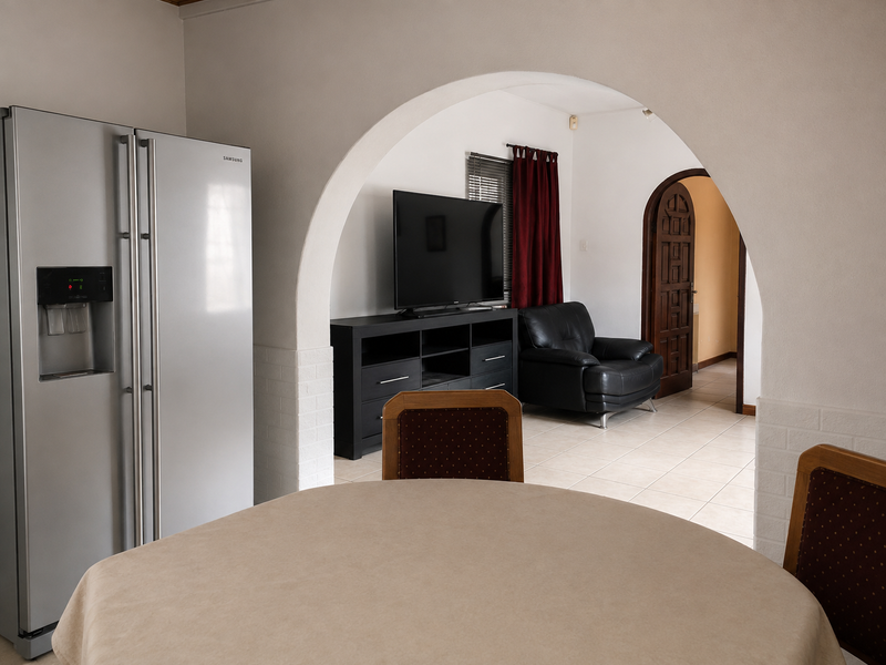 Open plan living area featuring a distinctive arched doorway connecting the dining space to the lounge, finished with neutral walls and tiled flooring.