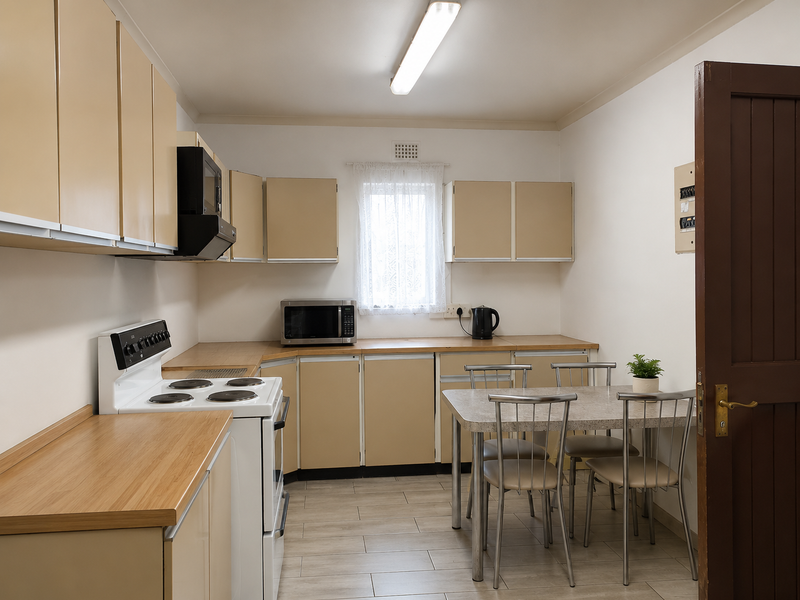 A functional kitchen featuring laminate cabinetry, wood-look laminate countertops, an electric stove with extractor fan, and tiled flooring.