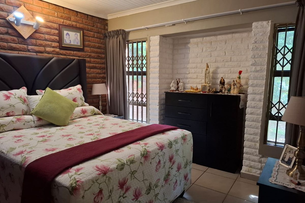 A bedroom featuring a rustic exposed brick feature wall, white painted brick alcove, tiled flooring, and security gates on the windows.