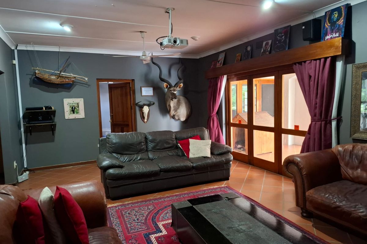 Spacious living room featuring dark grey walls, terracotta floor tiles, and large wooden-framed glass sliding doors leading to an outdoor area.