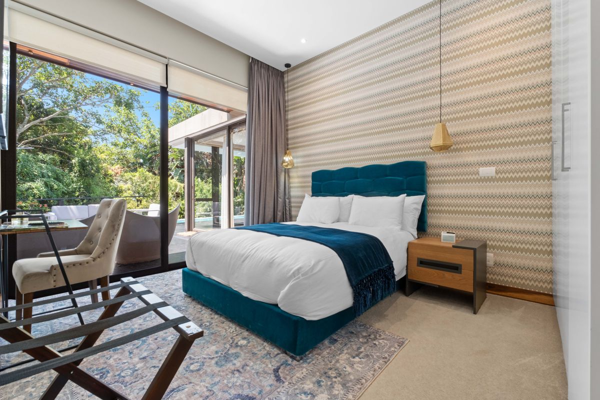 A well-appointed bedroom featuring large sliding glass doors that open onto a private patio, providing ample natural light and garden views.