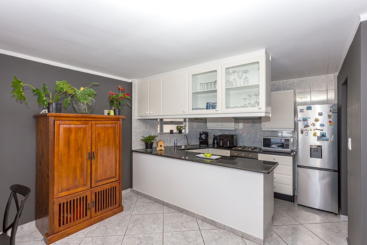 A functional kitchen featuring a breakfast bar, granite countertops, built-in cabinetry, and tiled flooring, offering a practical layout for daily meal preparation.