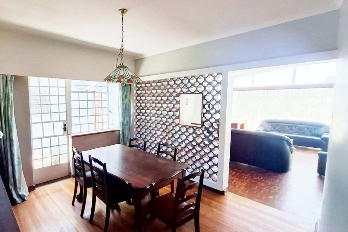 Open plan dining area featuring parquet and wooden flooring, separated by a decorative breeze block partition from the adjacent living space.
