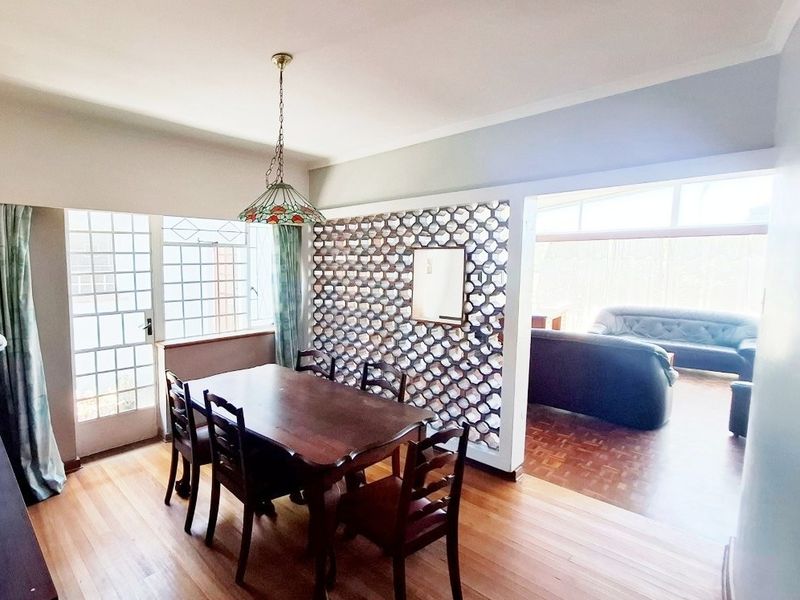 Open plan dining area featuring parquet and wooden flooring, separated by a decorative breeze block partition from the adjacent living space.