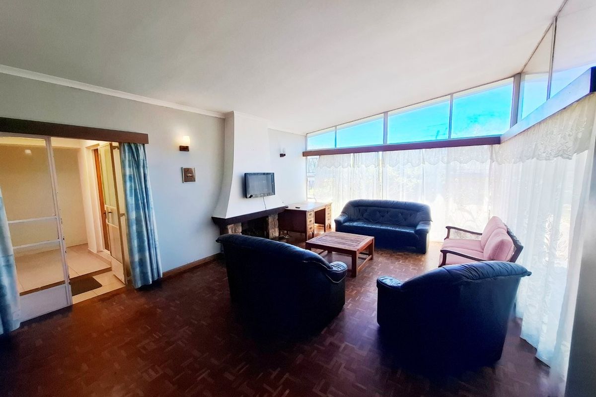 Spacious living room featuring original parquet flooring, a built-in fireplace, and expansive windows that provide abundant natural light.